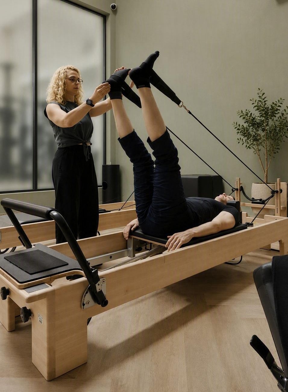 Kristin adjusting a client's feet in the reformer straps